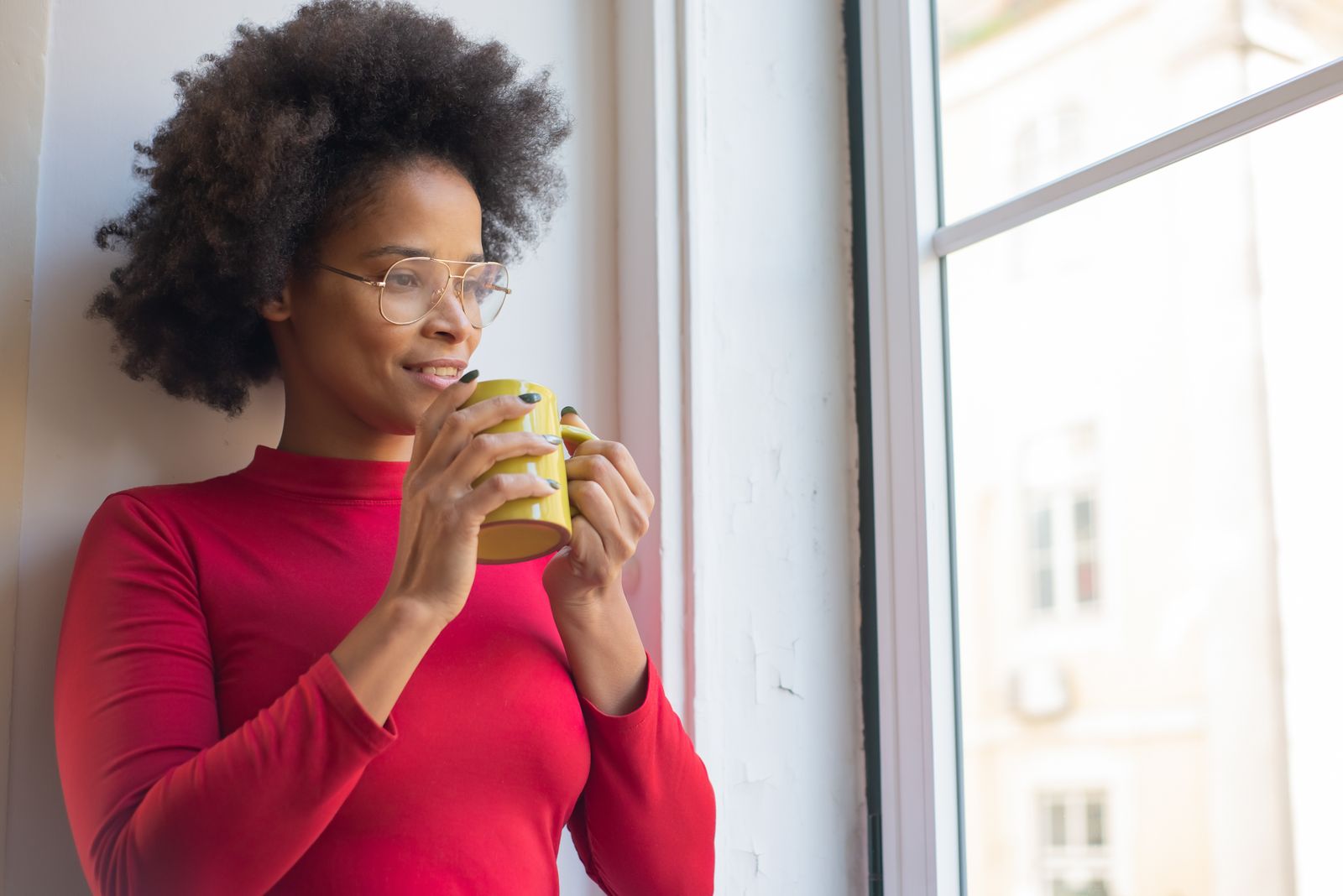 A woman enjoying her coffee by a sunny window